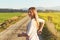 Young woman standing next to her bike at dusty country road, looking back over shoulder