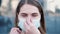 Young woman standing outside is sneezing and wearing a disposable mask