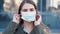 Young woman standing outside is sneezing and wearing a disposable mask