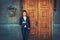 Young woman standing over old wooden door and texting on phone