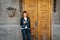 Young woman standing over old wooden door and texting on phone