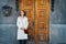 Young woman standing over yellow old wooden door, rusty postbox and concrete wall