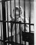 Young woman standing in a prison cell