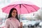 Young woman standing in rain with umbrella in her hands