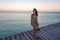 Young woman standing on seaside jetty at sunset