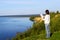 Young woman standing on the shore of the lake with blank sheet o