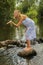 Young woman standing on stone in river, sending kiss