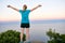 Young woman standing victoriously on a mountain top