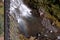 A young woman standing in a waters of Tumalo falls stream holding her hair.