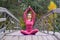 Young woman standing in yoga posture on wooden bridge in autumn