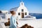 A young woman stands against a white church on the famous romantic island of Santorini