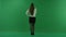 Young woman stands back to the camera, scrolls the screen and considers something on green screen