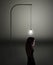 A young woman stands beneath a bright light bulb as she tries to come up with a new idea