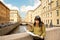 A young woman stands on a bridge on the Embankment of the Moika River with a view of the Hermitage in St. Petersburg and is