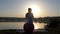 A young woman stands with a fitball on a lake bank