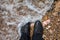 A young woman stands on a pebble beach in black leather sneakers on which a sea wave rolls - to leave the comfort zone