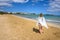 A young woman stands on the seafront.  Greece