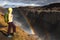 A young woman stands on the shore of the falling water of the most powerful waterfall in Europe - Dettifoss. Colorful summer day i