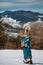 Young woman stands on snow against beautiful landscape of mountains