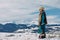 Young woman stands on snow against beautiful landscape of mountains