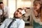 Young woman sticking note with word Fool to colleague`s face in office. Funny joke