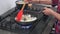 Young woman stirring fried onions in hot pan