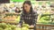 Young woman store worker in a brown apron at the department with fruits and vegetables