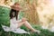 Young woman in a straw hat with long hair sits on the shore of the lake on grass and writes a letter. concept of romance