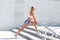 Young woman is streching outdoors on the stairs in sportswear and sunglasses