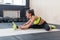 Young woman stretching hamstring in gym, fit female doing warm-up on mat