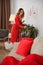 Young woman with string lights decorating room for Christmas