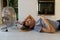 Young woman in striped t-shirt lies on floor by fan trying to cool down from stuffiness and summer heat