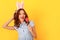 Young woman studio isolated on yellow wearing bunny ears eating lollipop looking aside