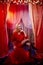 Young woman during a stylized theatrical circus photo shoot in a beautiful red location. Girl posing on stage with