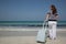 Young woman with suitcase on the beach