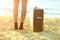 Young woman with suitcase standing on river shore