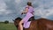 Young Woman in Summer Dress and Hat Riding Horse in Rural Field, Slow Motion