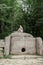 Young woman in summer dress sitting on a big dolmen stone in the forest looking away