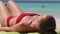 Young Woman Sunbathes on a Paradise Sandy Beach Lying in Red Swimsuit near Ocean