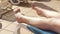 Young woman sunbathing on white plastic sunbed, detail to her moving feet