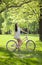 Young woman in sundress enjoying bike trip in park