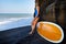 Young woman with surfboard walk on black sand beach