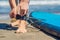 Young woman surfer getting on the surfboard`s leash