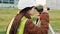 Young woman surveyor in green work clothes and helmet adjusts the equipment, produces calculations and writes to the