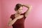 Young woman with sweat stain on her clothes against pink background