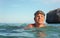 Young woman with swim goggles, surrounded by sea, closeup detail, rocky cliff and clear sky background