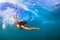 Young woman swim underwater, dive under ocean wave