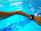 Young woman swimming in indoor pool with waterproof smart watch.