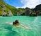 Young woman swims in the crystal clear water near of islands