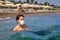 Young woman swims in the sea in a face mask